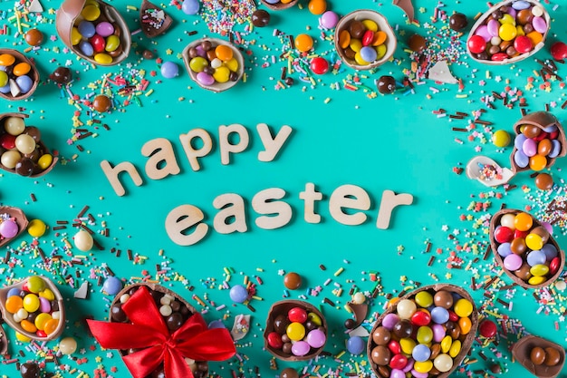 Cornice di pasqua con uova di cioccolato e dolci su sfondo rosa. testo di buona pasqua. vista dall'alto, distesa