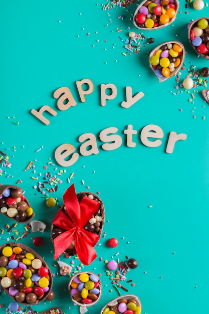 Easter frame with chocolate eggs and sweets on a pink background. Happy easter text. Top view, flat lay