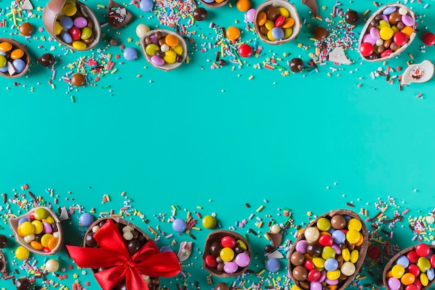Cornice di pasqua con uova di cioccolato e dolci su sfondo turchese, verde, blu. copia spazio, vista dall'alto, disposizione piatta