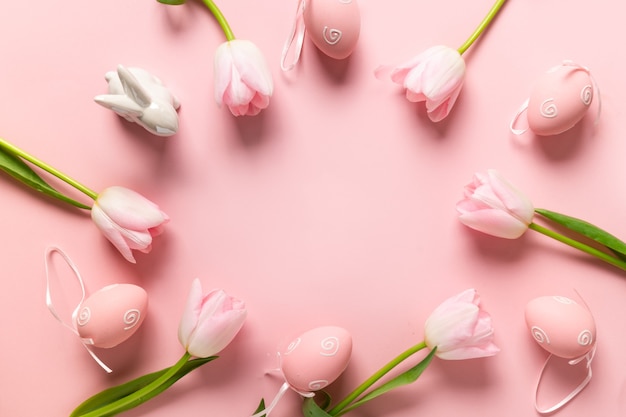 Easter frame with eggs, bunny, pink tulips on pink background.