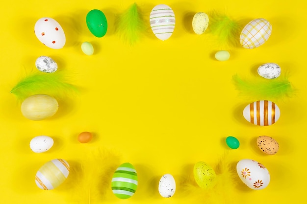 黄色の背景に卵と羽を持つイースター フレーム 最小限のコンセプト テキストのコピー スペース付きカードの上からの眺め