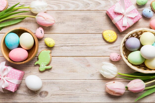 Photo easter frame with eggs gift box and tulip on a colored background the minimal concept top view happy easter composition card with a copy space of the place for the text