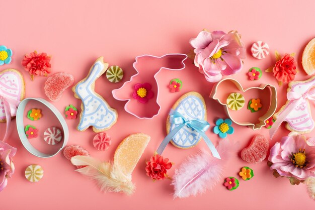 Easter frosted cookies in shape of egg chicken and rabbit sugar\
sprinkles candies cookie cutters on pink background flat lay\
mockup