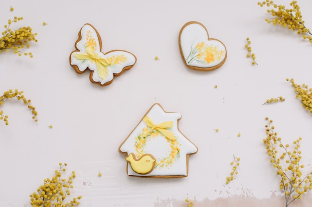 Easter gingerbread cookie and yellow mimosa florwers on white