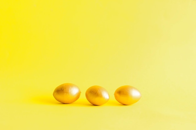 Пасхальные золотые декоративные яйца на желтом фоне