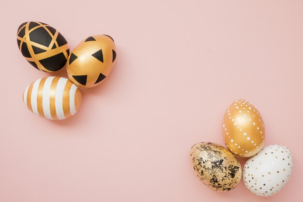 Easter golden decorated eggs on pastel pink background