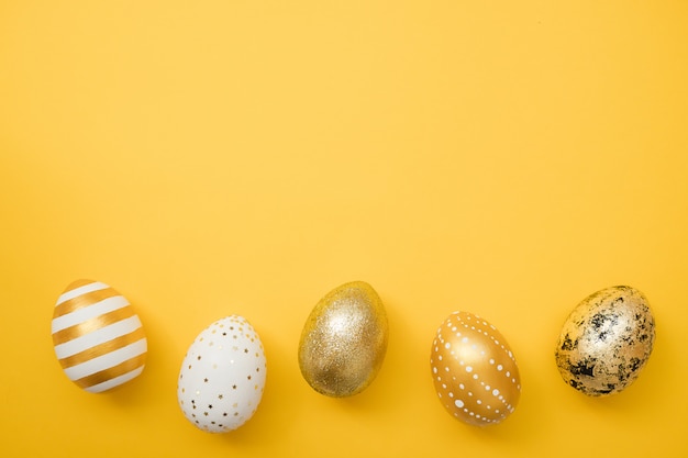 Easter golden decorated eggs on yellow background. Happy Easter card 