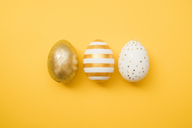 Easter golden decorated eggs on yellow background. Minimal easter 