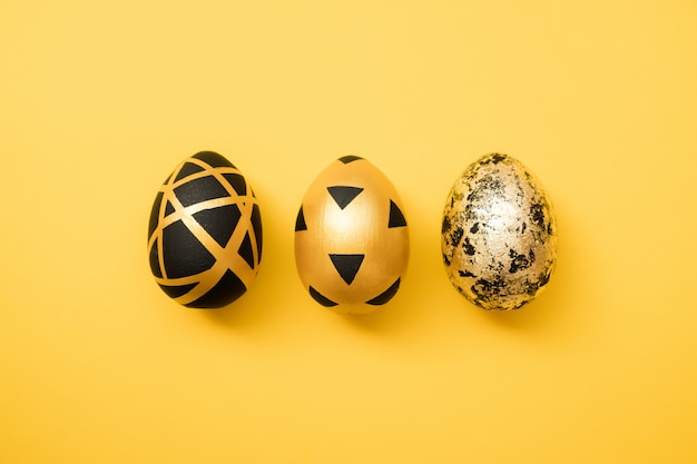 Easter golden decorated eggs on yellow background