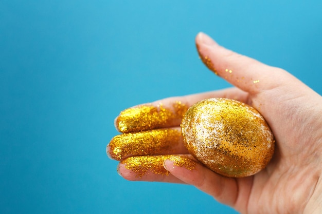 Easter golden egg in the hand on a blue background Easter background