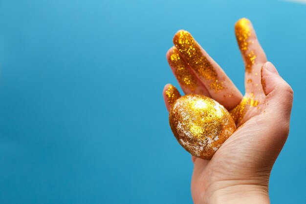 Easter golden egg in the hand on a blue background Easter background