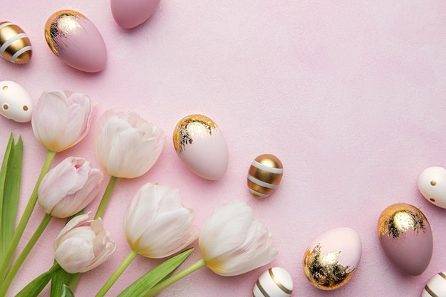 Uova d'oro di pasqua e tulipani rosa su sfondo rosa