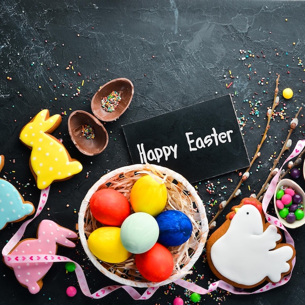 Easter greeting card Happy Easter Easter gingerbread cookies and decorative colored eggs On a black background Top view Free copy space