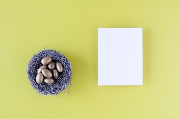 Easter greeting card with golden eggs in a nest on white background