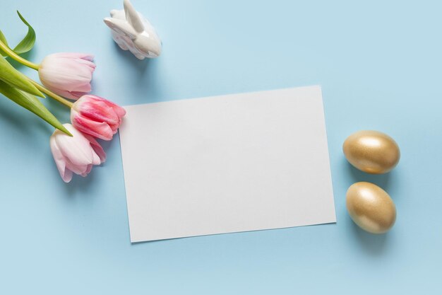 Easter greeting card with pink tulips bunny golden eggs on blue Text Happy Easter Top view