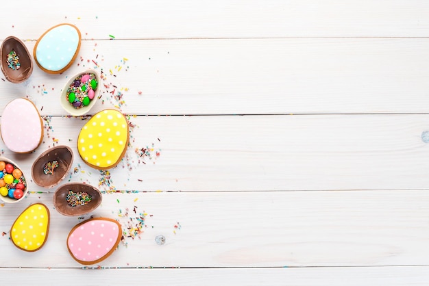 Easter greetings card with colorful gingerbread and sweets On a white wooden background Top view Free space for your text