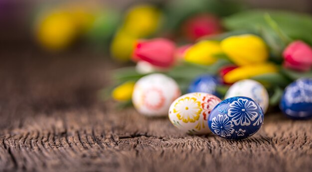 Easter. Hand made easter eggs and spring tulips on old wooden table.