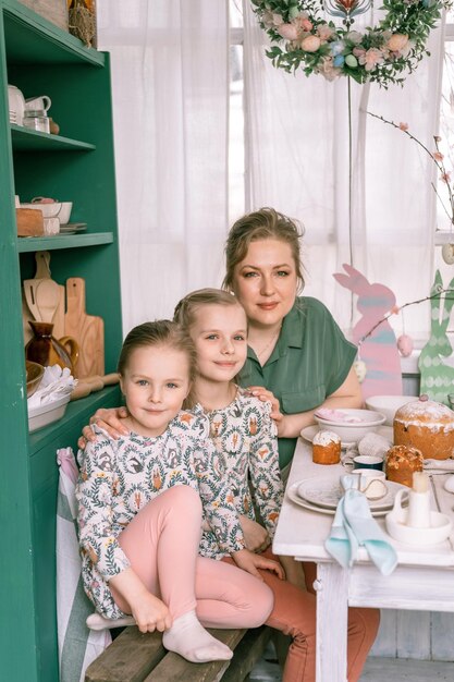 写真 イースターの幸せな家族のお母さんが一緒に小さな子供たちの女の子は楽しい春のイースター休暇を自宅で設定し、イースター ケーキ ベーカリーと塗られた卵でテーブルの景観を飾り、ランチやディナーに