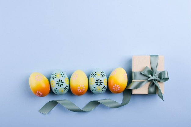 Easter holiday background  Top view of colorful painted chicken eggs plased  in a row and present box with ribbon