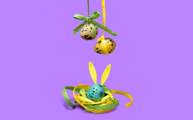 부활절 휴가 개념입니다. 재미있는 부활절 장식을 위한 보라색 배경의 둥지에 있는 귀여운 토끼 달걀