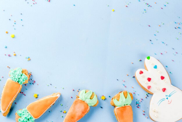 Easter holiday concept, sweet cookies in form of carrots, Easter bunny, with sweet sprinkles, light blue background copy space top view, greeting card background