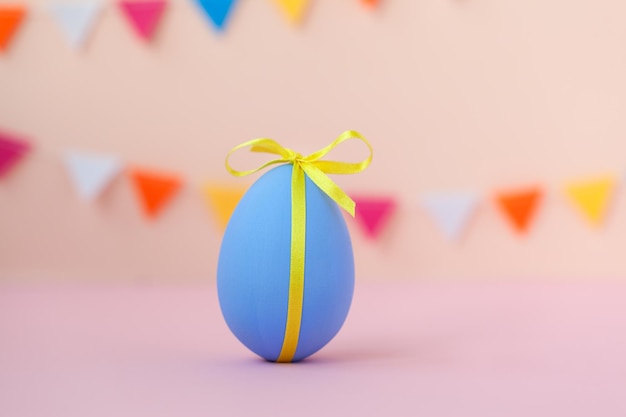 Concetto di vacanza di pasqua con decorazioni colorate uovo di pasqua blu con spazio per la copia su sfondo rosa.