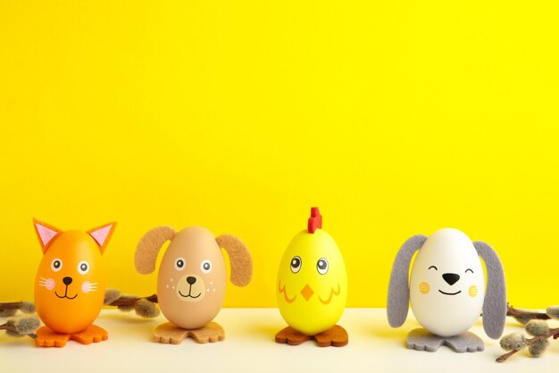 Easter holiday concept with cute handmade eggs, dogs, chicks and cat on yellow background. Top view. Happy Easter