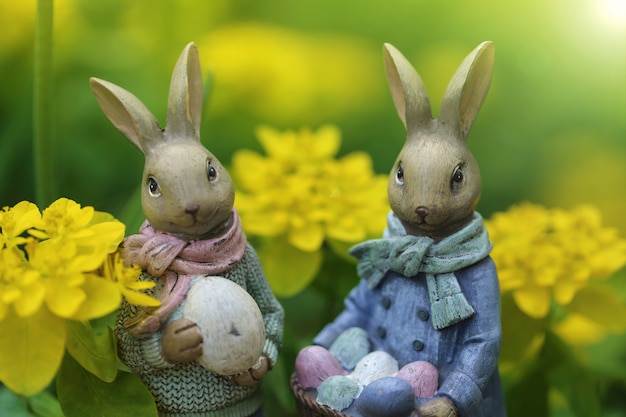 Easter holiday. Easter bunnies decorative on a blurred yellow floral nature in the rays of the sun.