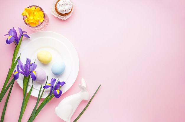 Easter holiday table setting and plates with colorful eggs on pink