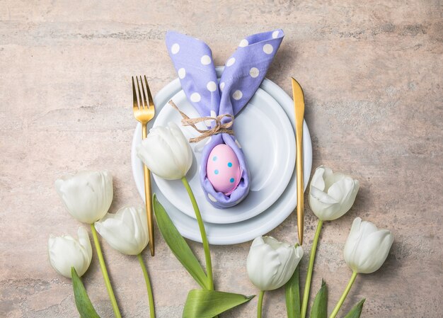 Foto regolazione della tabella di festa di pasqua con il coniglietto dall'uovo sulla zolla bianca e sui fiori dei tulipani.