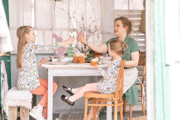 Foto tempo di vacanze di pasqua nella stagione primaverile famiglia felice candida bambini piccoli sorelle ragazze insieme madre si divertono a casa a decorare la tavola per il pranzo o la cena cibo tradizionale decorazioni per la casa festiva