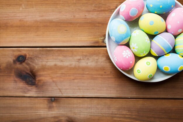 easter, holidays, tradition, advertisement and object concept - close up of colored easter eggs on plate