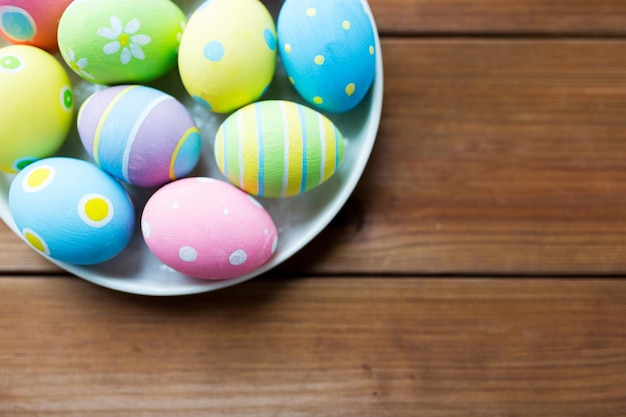 easter, holidays, tradition, advertisement and object concept - close up of colored easter eggs on plate