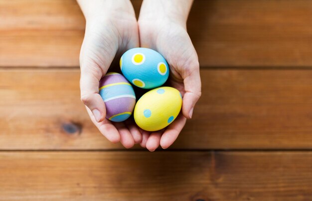 easter, holidays, tradition and people concept - close up of woman hands holding colored easter eggs