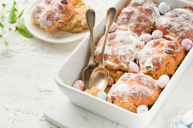 사진 이스터 핫 크로스  (easter hot cross buns) 전통적인 이스터 트리트 (traditional easter treats)  (cross buns with raisins butter chocolate candy eggs with blooming cherry or apple flowers on rustic light wooden backgrounds) 이스터 휴일 식사