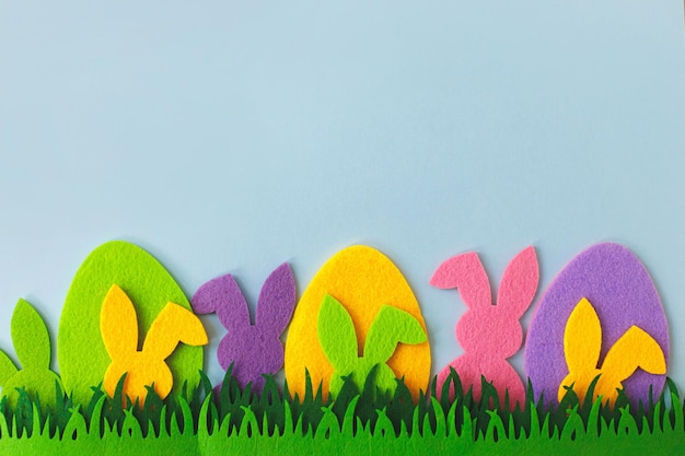 Easter hunt concept Colorful Easter bunnies and eggs in grass on blue background