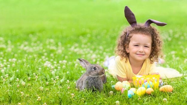 Foto pasqua bambino ragazza molto peri orecchie piccolo coniglio coniglio caccia uova colorate su erba verde vacanze di primavera