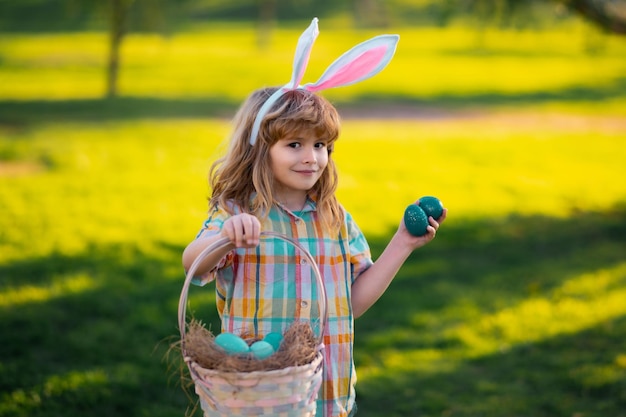 공원에서 부활절 달걀을 사냥 토끼 귀와 토끼 의상을 입은 아이 소년