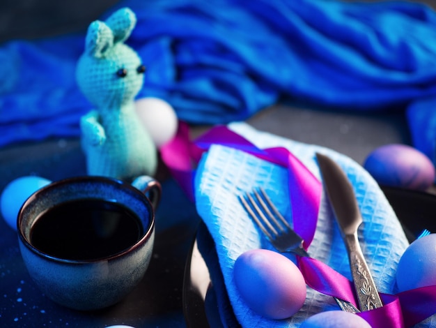 Пасхальный вязаный кролик раскрасил пасхальные яйца в черной тарелке чашка кофе эспрессо неоновый свет
