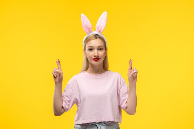 Easter lovely blonde adorable girl with pink bunny ears and red lipstick with crossed fingers