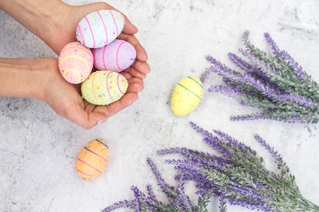 Easter multi-colored eggs in female hands on a background of flowers close-up