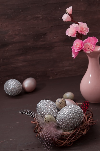 Easter nest with eggs on brown bakcground with pink blossom flowers low key still life