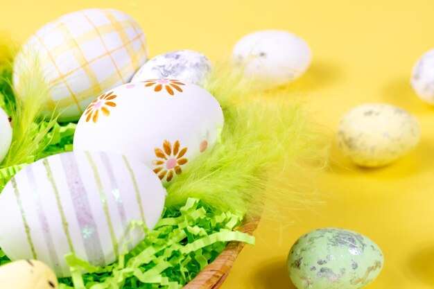 Easter nest with eggs and feathers on a yellow background closeup Minimal concept