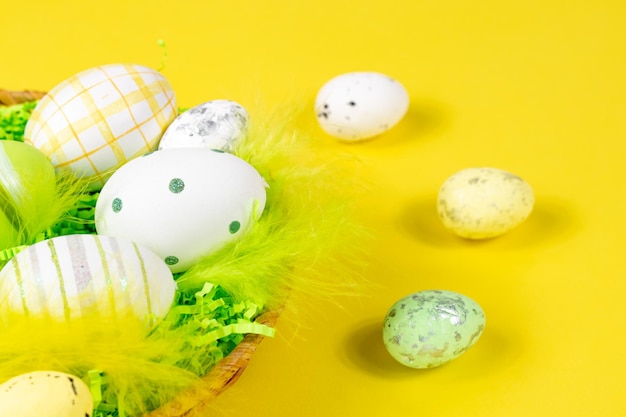 Easter nest with eggs and feathers on a yellow background closeup Minimal concept