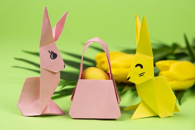 Easter origami two paper bunnies and an egg green background Crafts for the holiday do it yourself