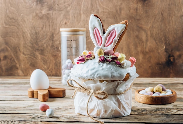 Easter Panettone or Kulich sweet bread decorated with bunny ears cookies mini chocolate eggs