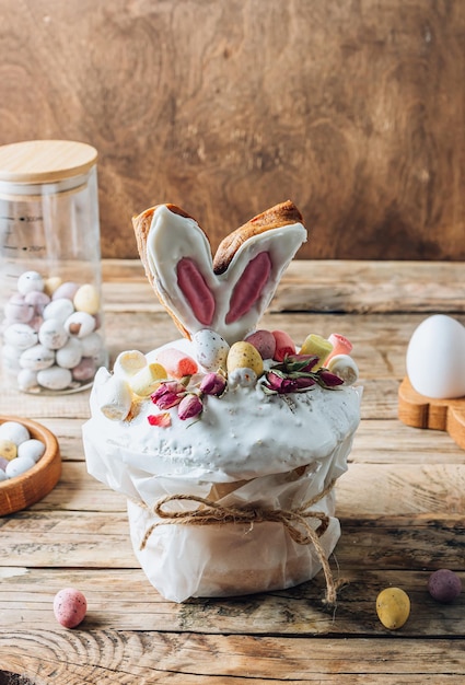 Easter Panettone or Kulich sweet bread decorated with bunny ears cookies mini chocolate eggs