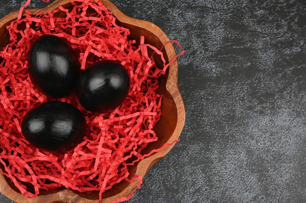 Easter pattern made of black eggs on dark background.