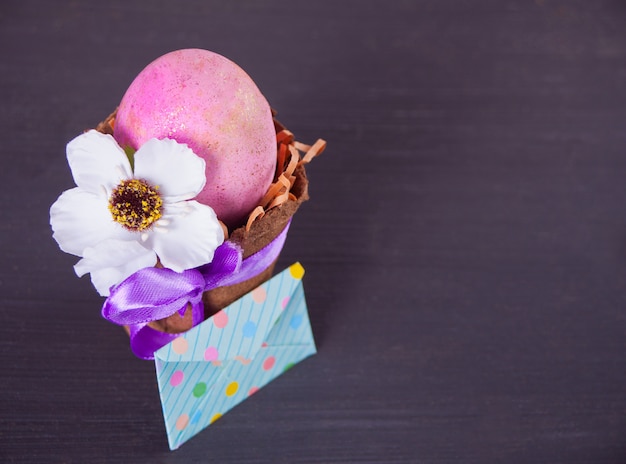 Easter pink egg in a pot with envelope on the black background