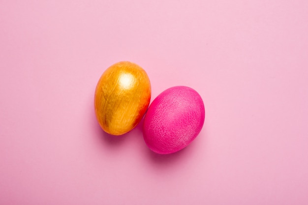 Uova di pasqua e oro rosa su una superficie rosa